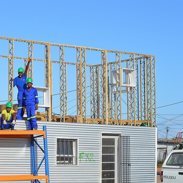 Builders erecting a house with eco-bricks and steel.