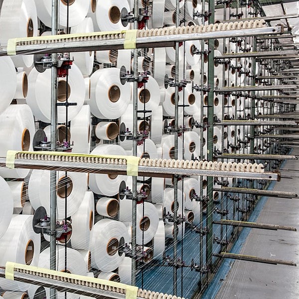 Round reels of nylon cord on an industrial loom at a textile supplier facility in South Africa.