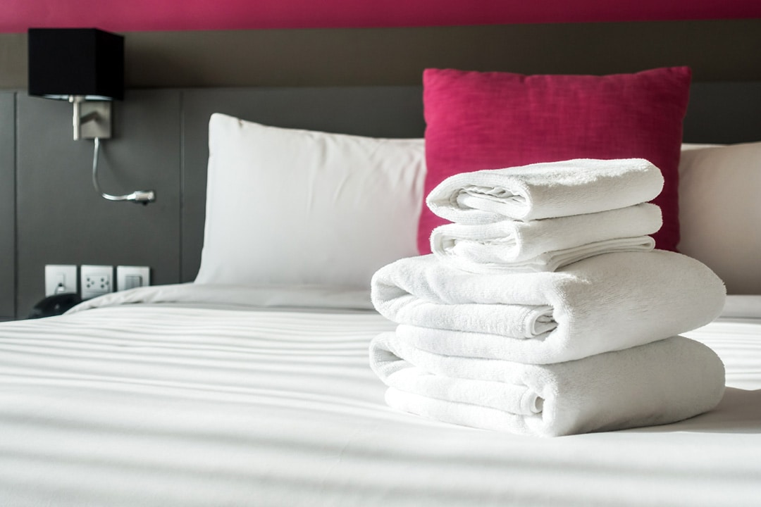 Romatex an important supplier for South African hospitality sector 6 Folded white towels on fresh white bed linen in a hotel room