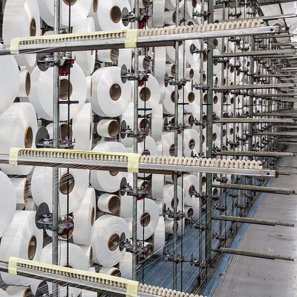 Round reels of nylon cord on an industrial loom at a textile supplier facility in South Africa.